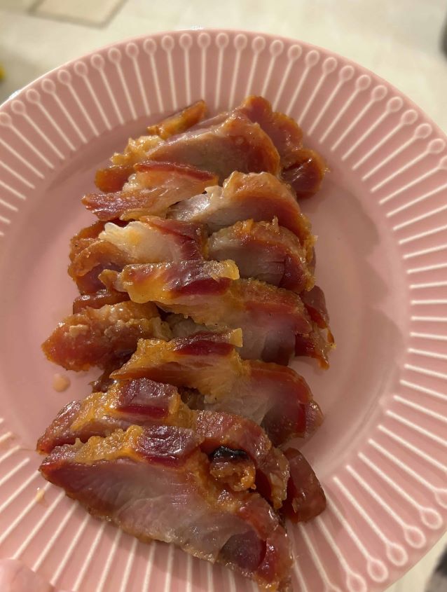 Slices of Char Sui, BBQ Pork on a pink plate.