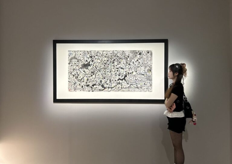 A woman looking at a painting on a wall.