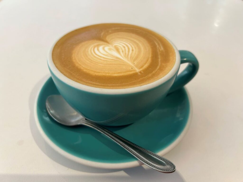 Flat white coffee in a green cup and saucer.