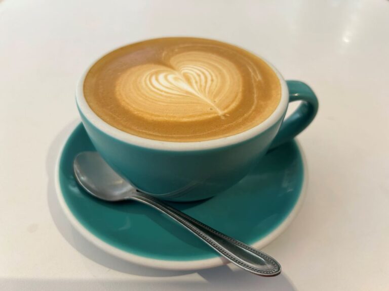 Flat white coffee in a green cup and saucer.