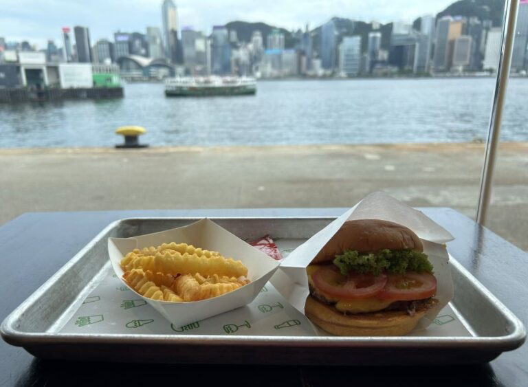 Crinkle-cut fries and a cheeseburger served at Shake Shack in Hong Kong’s Harbour City, with Victoria Harbour and the iconic skyline in the background—an affordable favorite among restaurants with a view.